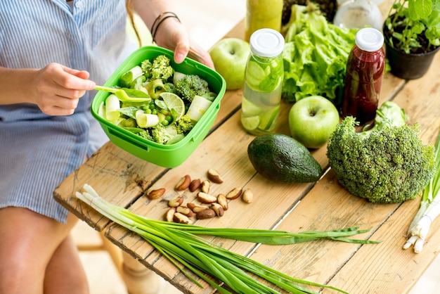 Salad with tomatoes and cheese in the bowl on the wooden table with green healthy ingredients. Healthy food concept