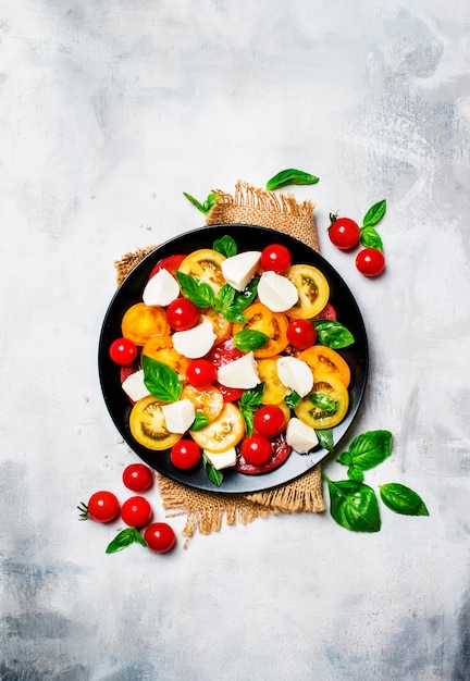 Salad with tomatoes mozzarella cheese and green basil gray background top view