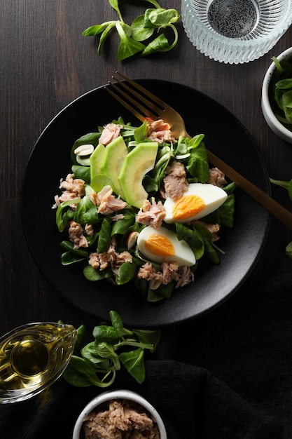 Salad with tuna on a dark table with a fork