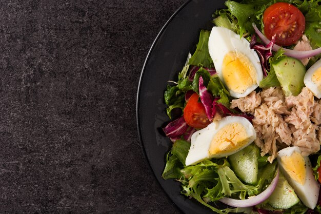 Salad with tuna, egg and vegetables on black