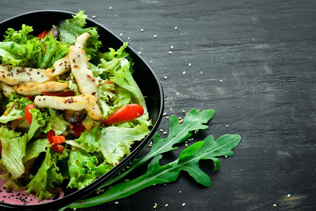 Salad with vegetables and chicken On a wooden background Top view Free space for your text