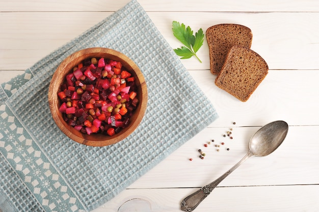 Salad in a wooden bowl on a wooden surface with black bread