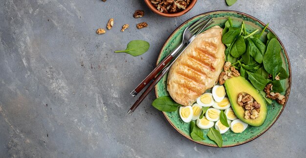 Salade avocado gegrilde kipfilet kwartel ei spinazie walnoot op een donkere achtergrond keto dieet Gezonde vetten schoon eten voor gewichtsverlies Lang bannerformaat bovenaanzicht