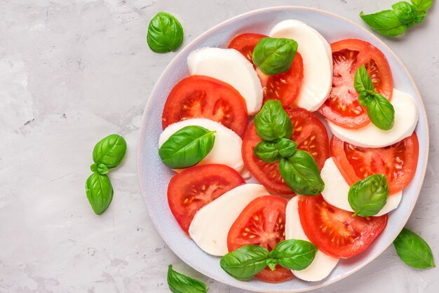 Salade caprese met rijpe tomaten en mozzarellakaas, verse basilicumbladeren. Italiaans eten