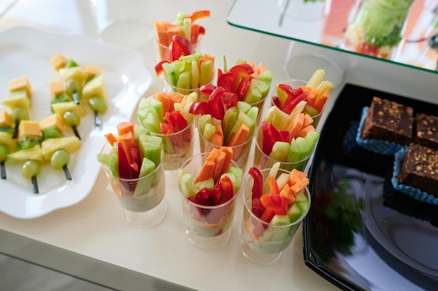 Foto salade gesneden uit verschillende soorten groenten, netjes opgemaakt in een plastic glas om te serveren