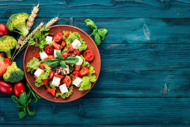 Salade in een bord Feta kaas cherrytomaatjes paprika sla Gezonde voeding Op een blauwe houten tafel tafel Bovenaanzicht Vrije ruimte voor tekst