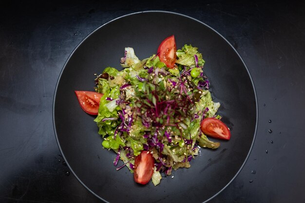 Salade in een zwarte plaat op een zwarte houten achtergrond