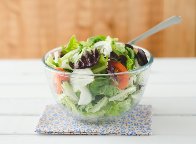 Salade in glazen kom op witte houten