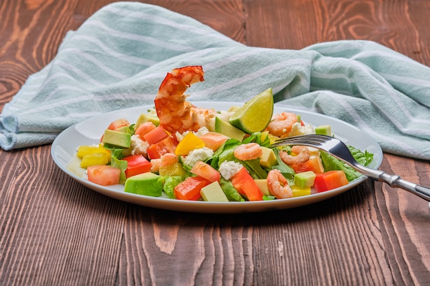 Salade met avocado, feta-kaas en garnalen op oude houten tafel