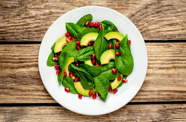 salade met avocado, rucola, spinazie, granaatappel, zaden op houten achtergrond