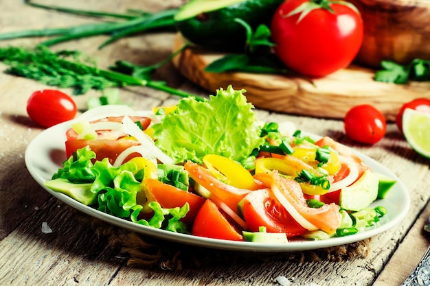 Salade met avocado zalmsla uien en paprika's op een plaat oude houten achtergrond selectieve focus