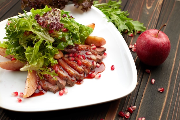 Salade met eendborst suvid op een houten lijst