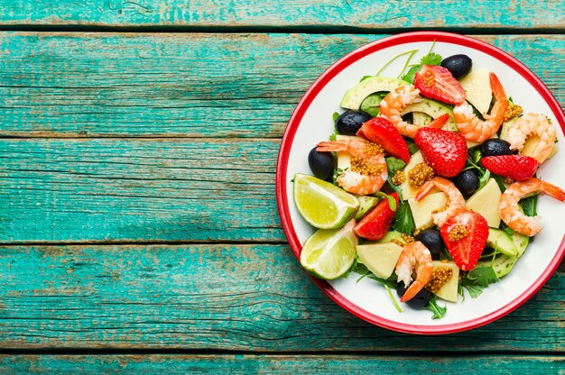 Salade met garnalen, aardbeien, avocado en kruiden Zeevruchtensalade op rustieke houten achtergrond Kopieer ruimte, ruimte voor tekst
