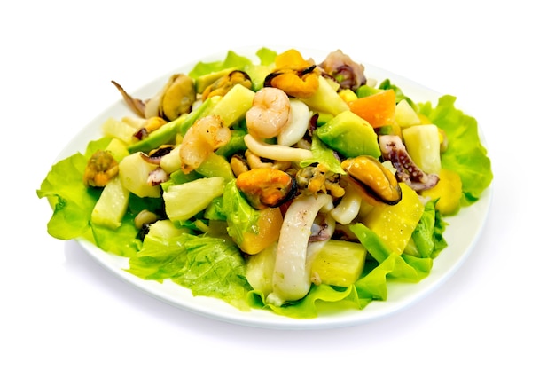 Salade met garnalen, octopus, mosselen en calamares met avocado, sla, ananas in een kom geïsoleerd op een witte achtergrond