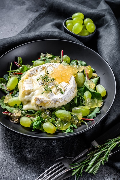 Salade met gebakken camembert, druiven, snijbiet en rucola. Zwarte achtergrond. Bovenaanzicht