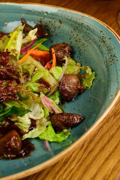 Foto salade met gebakken champignons, tomaten en sla op een houten tafel, bovenaanzicht