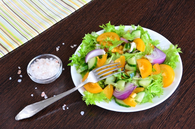 salade met gele tomaat, ui, komkommer en slablaadjes met vork