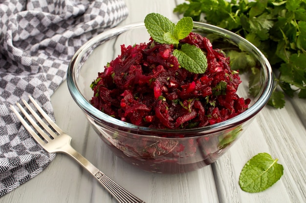 Salade met geraspte bieten en kruiden in de glazen kom op de grijze houten