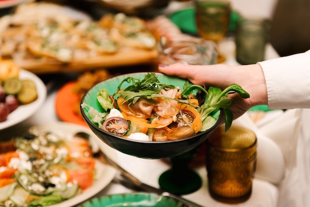 Salade met groenten, kruiden en kaas die de ober op tafel zet