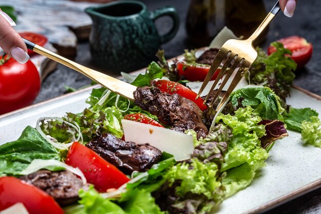 Salade met kippenlever. Verse groentesalade. Vleessalade met lever, slabladeren, kaas, tomaten op plaat. Dieetmenu. Bovenaanzicht