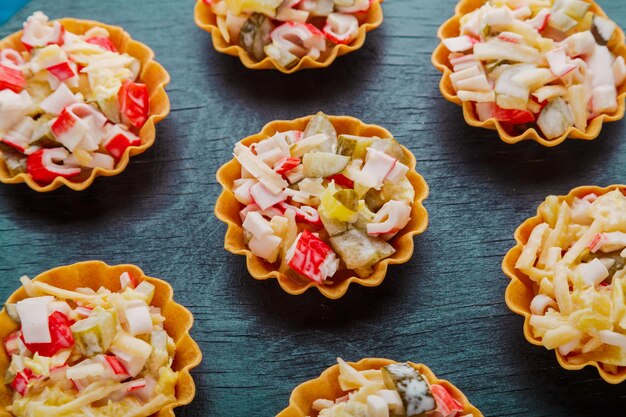 Salade met krab in tartlets op een zwarte close-up als achtergrond.