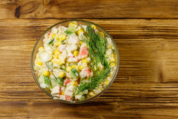 Salade met krabstokken suikermaïs komkommer eieren rijst en mayonaise op houten tafel Bovenaanzicht