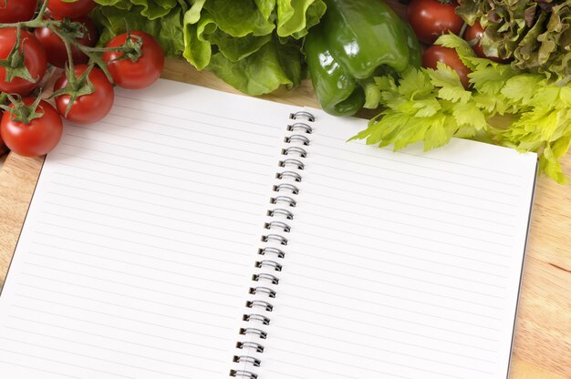 Salade met lege receptenboek en snijplank