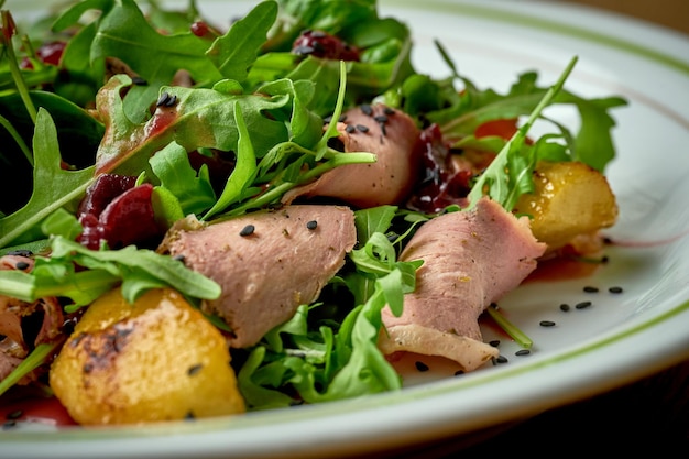 Salade met rosbief rucola gekarameliseerde uien in een bord op een houten achtergrond