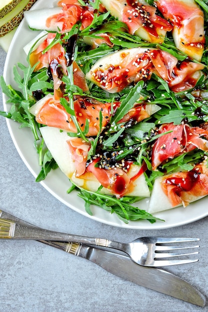 Salade met rucola, meloen en prosciutto. Keto-dieet. Paleo dieet. Pegan-dieet. Het concept van een mooie en heerlijke dieetvoeding.