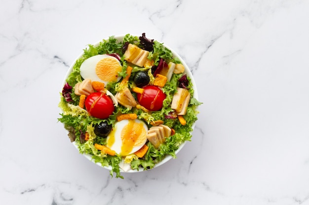 Foto salade met sla ei tonijn olijven en honing en mosterd vinaigrette op witte achtergrond