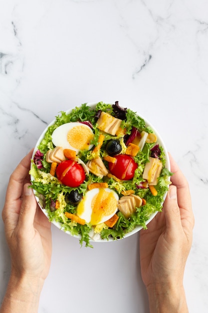 Salade met sla ei tonijn olijven en honing en mosterd vinaigrette op witte achtergrond