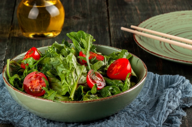Salade met tomaten, rucola en spinazie op een zwarte houten tafel