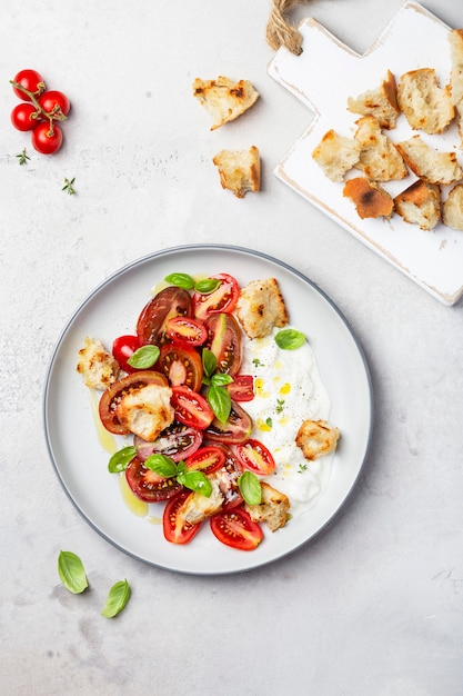 Salade met tomaten, stracciatella, ciabatta en basilicum op een lichte achtergrond