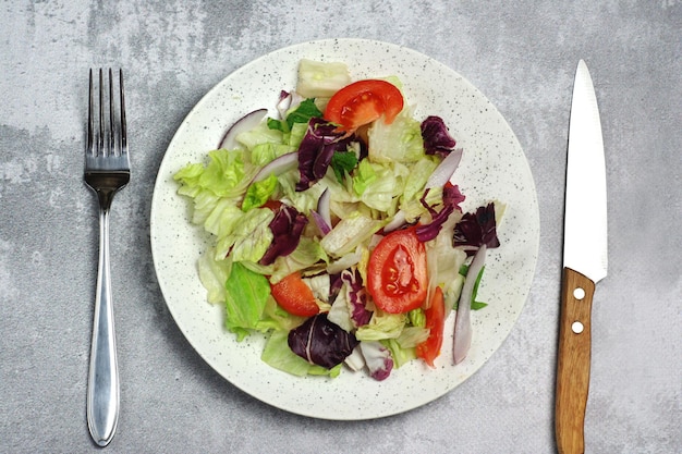 Salade met tomatenbladeren in een bord op tafel Er is een vork en een mes in de buurt