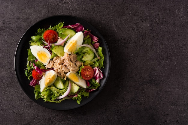 Salade met tonijn, ei en groenten op zwart