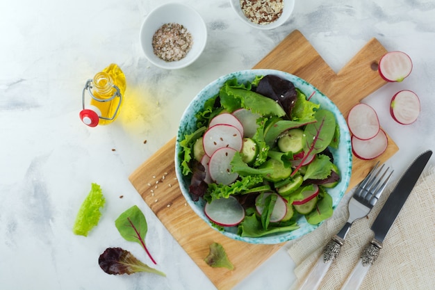 Salade met verse radijs, rucola, bieten, snijbiet, zonnebloempitten, lijnzaad en sesamzaadjes op een lichte achtergrond