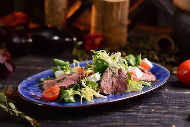 Salade met vlees, sla, kerstomaatjes en kaas. In de blauwe plaat