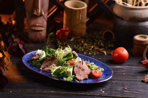 Salade met vlees, sla, kerstomaatjes en kaas. In de blauwe plaat