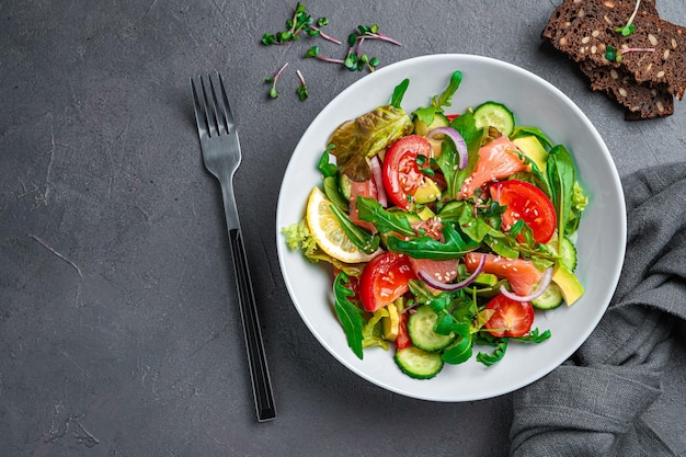 Salade met zalm, avocado, komkommer en tomaten op een grafietachtergrond Bovenaanzicht kopieerruimte