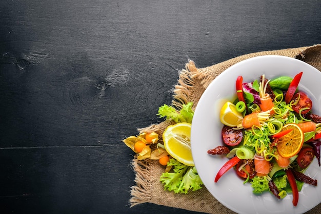 Salade met zalm en verse groenten en kruiden Italiaanse keuken Bovenaanzicht op houten achtergrond