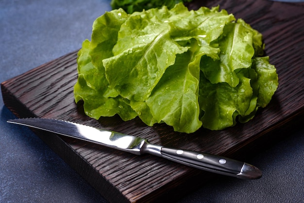 Salade, peterselie en dille op een donkere snijplank tegen een blauwe betonnen achtergrond