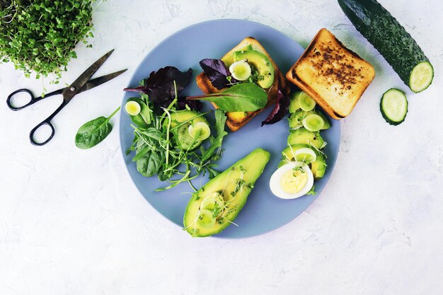 Salade van avocado, gekookte eieren, prei, microgreens spruitjes en rucola, op een bord op een lichttafel