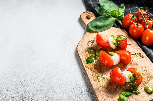 Salade van caprese aan het spit, tomaat, pesto en mozzarella. canapeetjes snack. grijze achtergrond. bovenaanzicht. kopieer ruimte