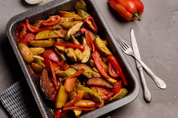 Salade van gegrilde groenten met courgette, aubergine, paprika en tomaat op grijze achtergrond