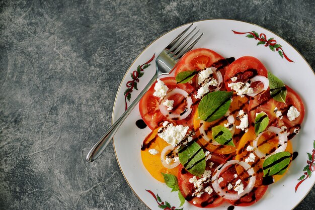 Salade van gele en rode tomaten met basilicum, zachte kaas en uien