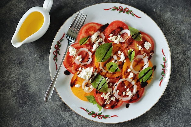 Salade van gele en rode tomaten met basilicum, zachte kaas en uien