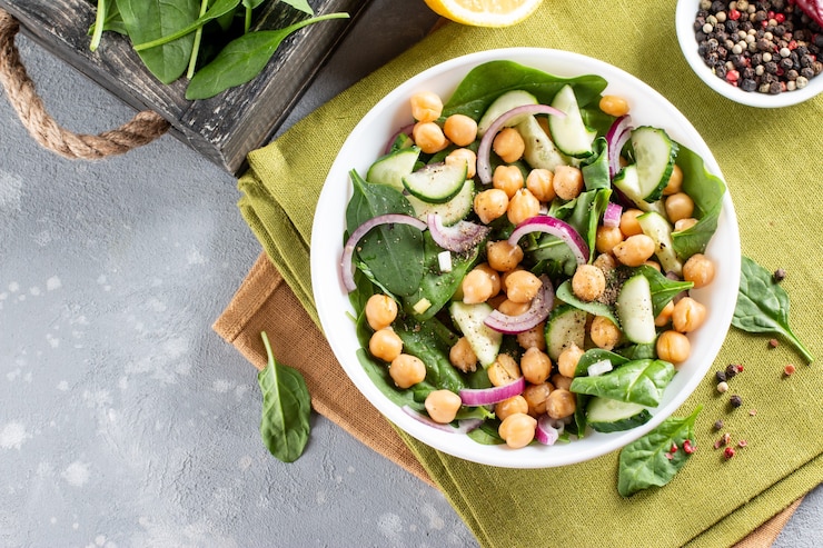 Foto salade van kikkererwten, spinazie, komkommers, uien en groenten in een bord