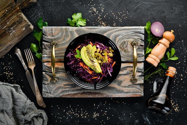 Salade van paarse kool, wortelen, avocado's en pompoenpitten Bovenaanzicht Op een zwarte achtergrond Gratis kopieerruimte