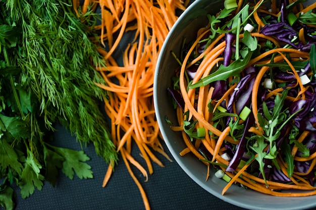 Salade van rode kool, wortelen en greens. Gedecoreerd met gesneden groenten en kruiden. Stroken snijden.
