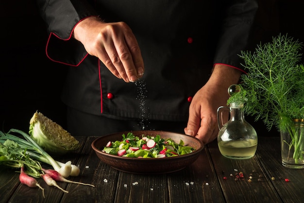 Salade van verse groenten moet gezouten worden de chef voegt zout toe aan een bord met een heerlijke salade